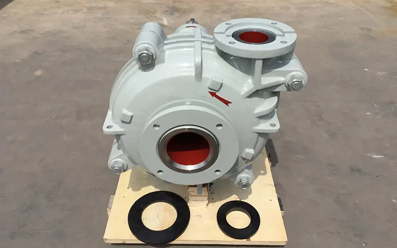 Light gray horizontal slurry pump with red rotation arrow, placed on wooden pallet with gaskets.