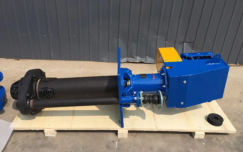 Blue vertical slurry pump with long shaft and yellow guard, placed on wooden pallet.