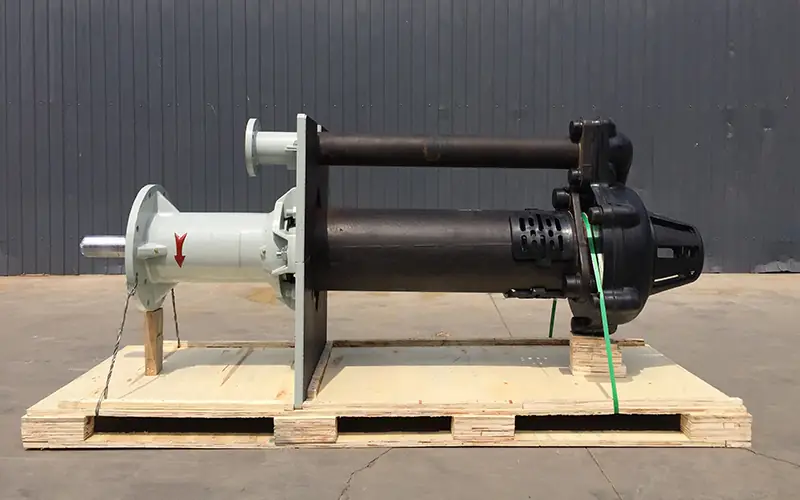 Vertical slurry pump with dual shafts, white upper section and black pump head, mounted on wooden pallet.
