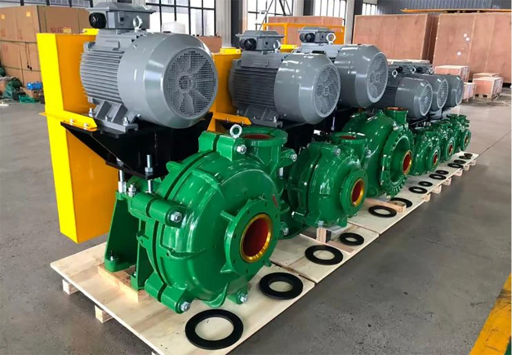 Row of green horizontal slurry pumps with electric motors on wooden pallets ready for delivery