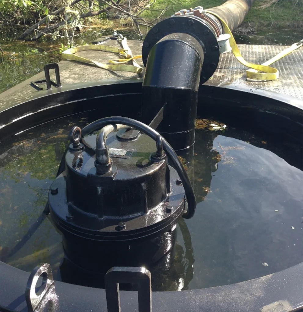 Submersible sewage pump operating in a wastewater collection tank with elbow discharge pipe