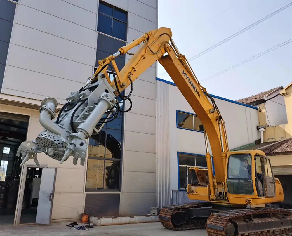 A custom gray hydraulic excavation tool mounted on the arm of a modern yellow excavator, featuring cutting blades, gripping claws, and a central cutting head.