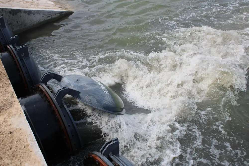 Submersible axial flow pump operating in a water channel, generating strong water flow and turbulence at the outlet.