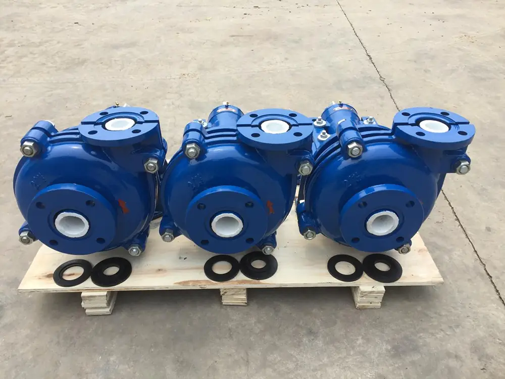 three blue horizontal centrifugal slurry pump casings with white lined ports arranged on a wooden pallet, with black rubber gaskets placed in front.