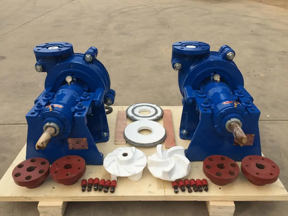 two blue centrifugal pumps displayed on a wooden pallet alongside spare impellers, flanges, and components